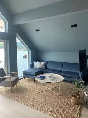 a living room with a blue couch and a table at Måløy Fjordbuer moderne og luksuriøse med havutsikt in Måløy