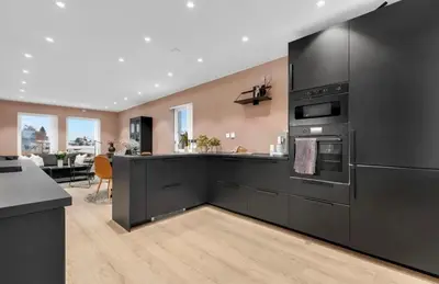 a kitchen with black appliances and a living room at Upgraded 3 bedroom apartment, close to WC-25 in Trondheim