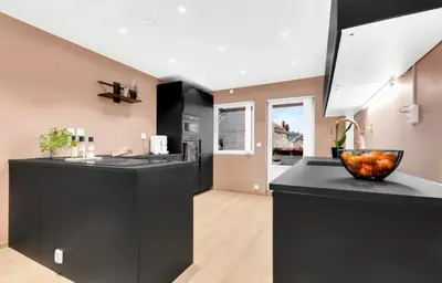 a kitchen with black cabinets and a bowl of fruit on the counter at Upgraded 3 bedroom apartment, close to WC-25 in Trondheim