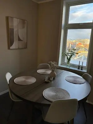 a dining room table with chairs and a large window at Apartment Solsiden Trondheim in Trondheim