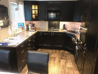 a kitchen with black cabinets and a wooden floor at Hessdalen hytte in Vårhus
