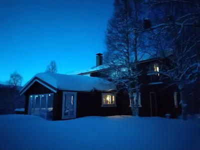 a house covered in snow at night at Hessdalen hytte in Vårhus