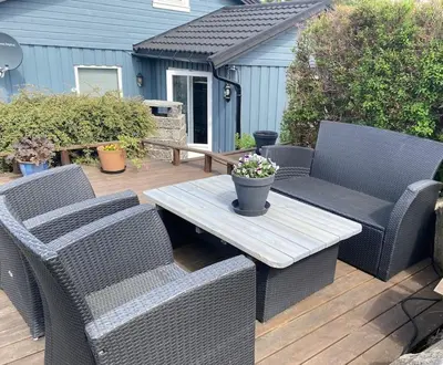 two wicker chairs and a table on a wooden deck at Cozy apartment near city center and nature in Kristiansund