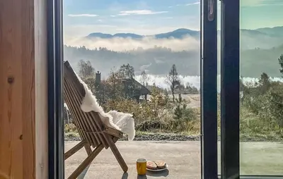 a chair sitting on a porch looking out a window at Nice Home In Edland With Sauna in Nesland