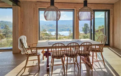 a dining room with a table and chairs and windows at Nice Home In Edland With Sauna in Nesland