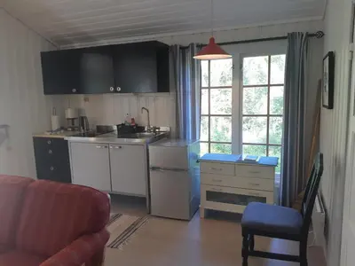 a kitchen with white cabinets and a table and a chair at Eidsdal Camping og Feriehus in Eidsdal