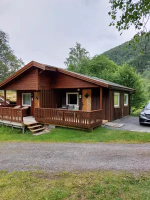 a large wooden cabin with a car parked in front of it at Eidsdal Camping og Feriehus in Eidsdal