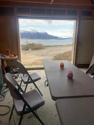 a table and chairs in a room with a large window at Villa med sauna ute, egen båt, naust og kai in Breidvik