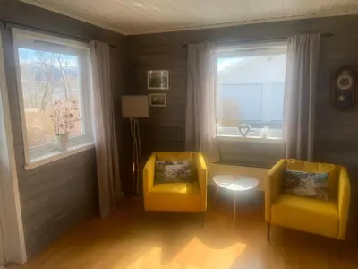 two yellow chairs in a room with a window at Villa med sauna ute, egen båt, naust og kai in Breidvik