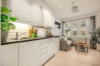 a kitchen with white cabinets and a living room at Flat in Bergen house with outstanding roof terrace in Bergen