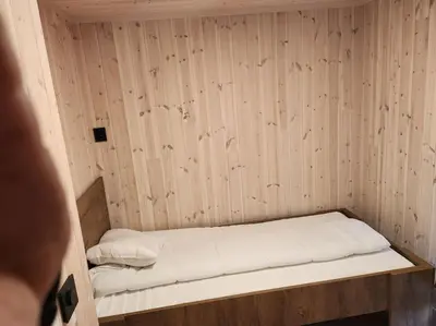 a small room with a bed in a wooden wall at Nyoppført hytte med mulighet til å leie badestamp in Levanger