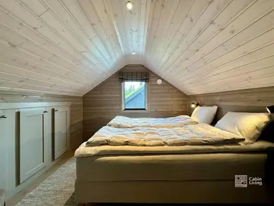 a large bed in a room with a wooden ceiling at High standard cabin at Sjusjøen sauna, hot tub & ski trails right outside in Ringsaker
