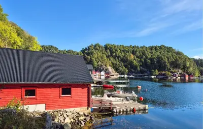 a red building on the water next to a dock at 3 Bedroom Amazing Home In Reksteren in Haukafer
