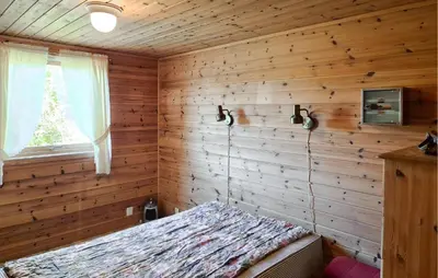 a bedroom with wooden walls and a bed in a room at 3 Bedroom Amazing Home In Reksteren in Haukafer