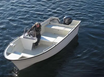 a man standing in a boat in the water at Hareid in Hareid