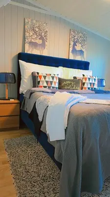 a bed with a blue head board in a bedroom at Room In Handsome Haven House in Gjøvik