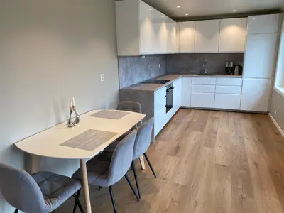 a kitchen with white cabinets and a table and chairs at Leilighet på Hardbakke in Lia