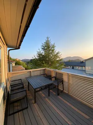 a wooden deck with a picnic table and two benches at Leilighet på Hardbakke in Lia