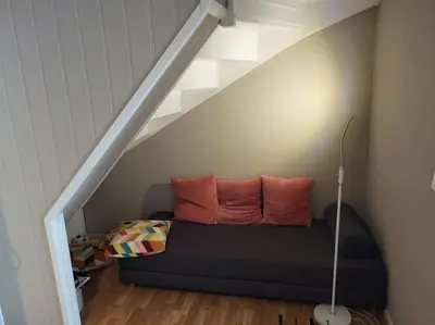 a couch with two pillows sitting under a staircase at Koselig familiebolig Granåsen in Trondheim