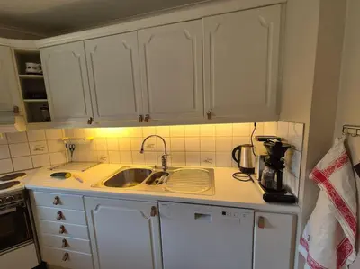 a kitchen with white cabinets and a sink at Cozy Home with Sauna, river views and 10 min from Hafjell and Lillehammer in Fåberg
