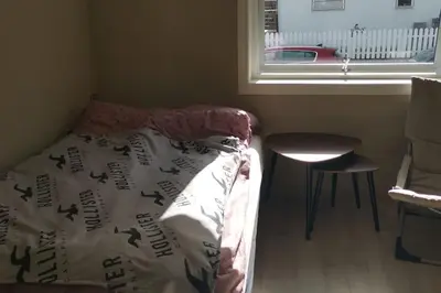 a bedroom with a bed and a chair and a window at Koselig leilighet nær sentrum in Laksevag