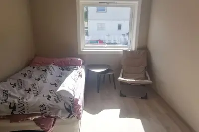 a bedroom with a bed and a window and a chair at Koselig leilighet nær sentrum in Laksevag