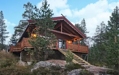 a log cabin in the woods with a staircase leading up to it at Gorgeous Home In Tuddal in Tuddal