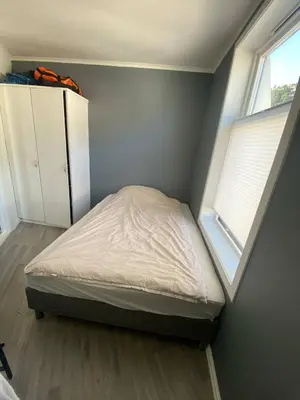 a small bedroom with a bed and a window at Flott leilighet med herlig utsikt in Ålesund