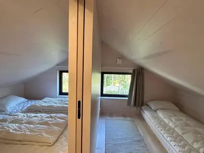 an attic bedroom with two beds and a window at Tyristua in Gjesval