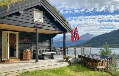 a log cabin with a flag on the porch at Stunning Home In Todalen in Ålvundfjord