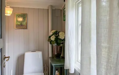 a bathroom with a vase of flowers on a table next to a window at Cozy Home In Sjusjøen With Sauna in Sjusjøen