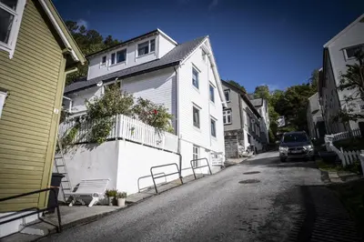 a white house with a car parked on a street at Koselig leilighet i sentrum in Ålesund