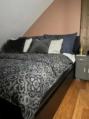 a bed with a black and white blanket and pillows at Villa apartment in Trondheim