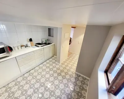a kitchen with white cabinets and a tile floor at OAH 1870 Oldest Alesund House in Ålesund