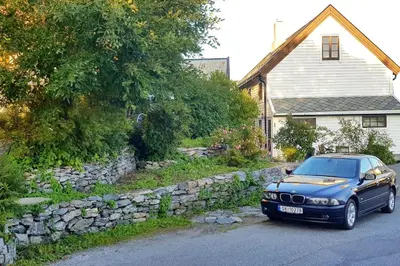 a blue car parked in front of a stone wall at OAH 1870 Oldest Alesund House in Ålesund