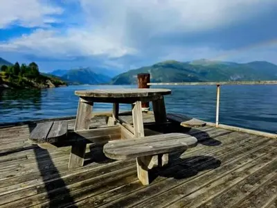 a picnic table and bench sitting on a dock at Seaside 3-bedroom Holiday home in Balestrand