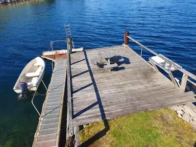 a boat is docked at a dock on the water at Seaside 3-bedroom Holiday home in Balestrand
