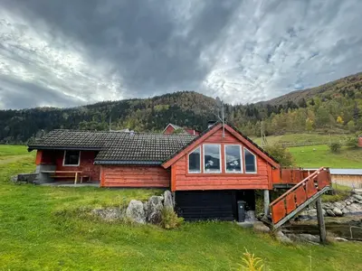 a small wooden house in a grassy field at Seaside 3-bedroom Holiday home in Balestrand