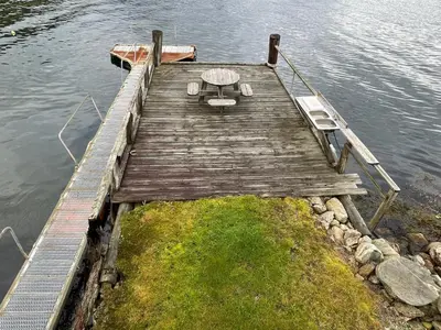 a wooden dock with a table and chairs on the water at Seaside 3-bedroom Holiday home in Balestrand