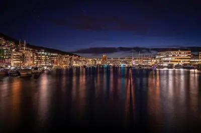 a city lit up at night with a harbor at Dining Apartments l Restaurants with sea I City Traveller & Workspace in Bergen