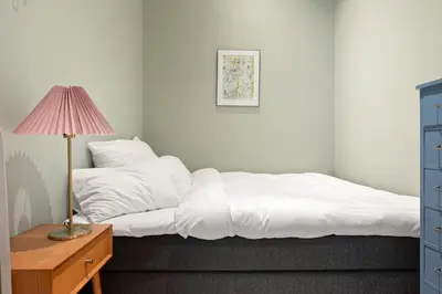 a bedroom with a bed with white sheets and a lamp at Dining Apartments l Restaurants with sea I City Traveller & Workspace in Bergen