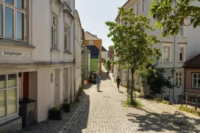 an empty street with buildings and a person walking down a street at Dinbnb Appartments l Live in a postcard ! l 300 m To Bryggen l Value! in Bergen