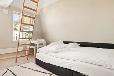 a bedroom with a ladder and a bed with white sheets at Dinbnb Appartments l Live in a postcard ! l 300 m To Bryggen l Value! in Bergen