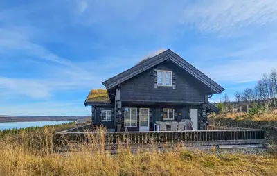 a house with a grass roof on a hill next to a lake at Gorgeous Home In Gol With Sauna in Gol