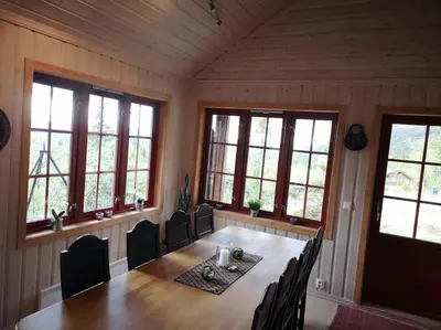 a dining room with a table and chairs and windows at Høyfjellshytte in Flå