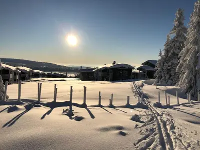 a fence in the snow with the sun behind it at Leilighet sentralt på Sjusjøen, 11 sengeplasser in Ringsaker