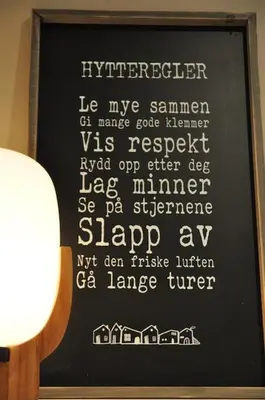 a black sign with white writing on a wall at Leilighet sentralt på Sjusjøen, 11 sengeplasser in Ringsaker