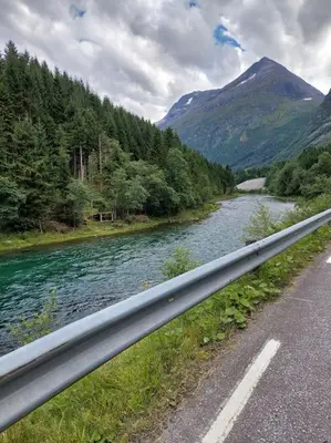 a river next to a road next to a mountain at Jovollstua i Eresfjord med båt til leie in Øverås
