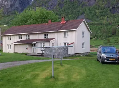 a car parked in front of a white house at Jovollstua i Eresfjord med båt til leie in Øverås