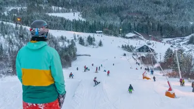 a man is looking at a group of people on a ski slope at Vassfjellet Home in Trondheim